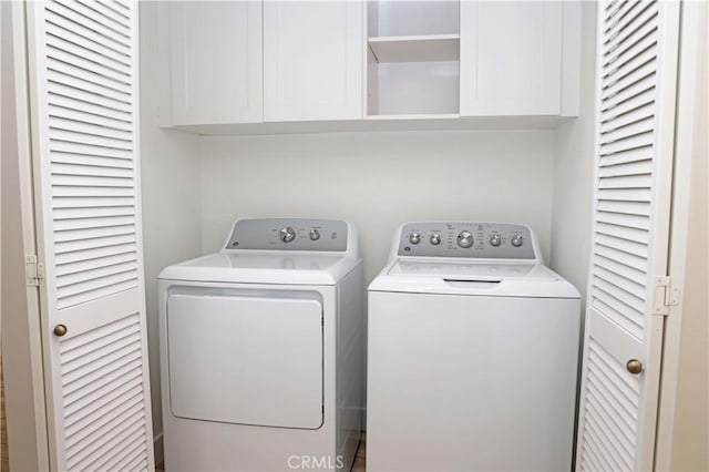 clothes washing area with washer and dryer and cabinets