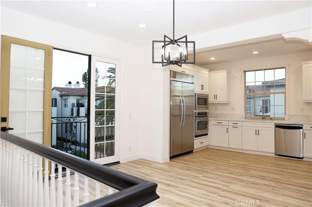 kitchen featuring built in appliances, white cabinetry, and hanging light fixtures