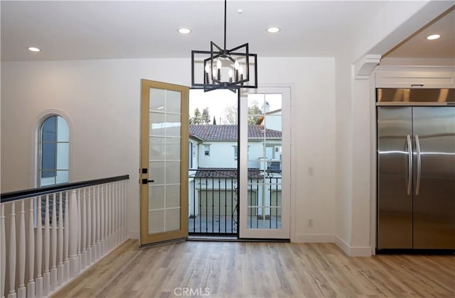 doorway featuring light wood-type flooring, french doors, and a chandelier