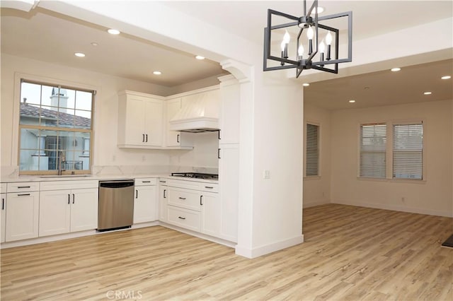 kitchen featuring sink, white cabinets, custom exhaust hood, hanging light fixtures, and appliances with stainless steel finishes