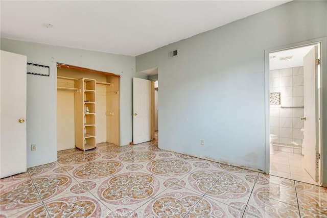 unfurnished bedroom featuring tile patterned floors, a closet, and ensuite bath