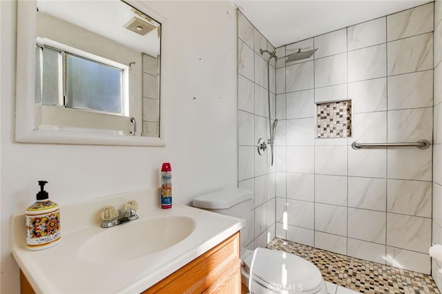 bathroom featuring toilet, vanity, and a tile shower