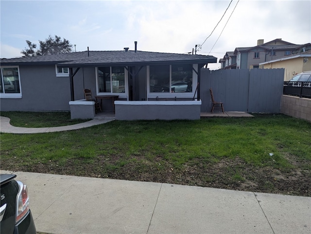 rear view of property with a lawn, a sunroom, and a patio