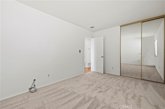 unfurnished bedroom with light carpet and a closet