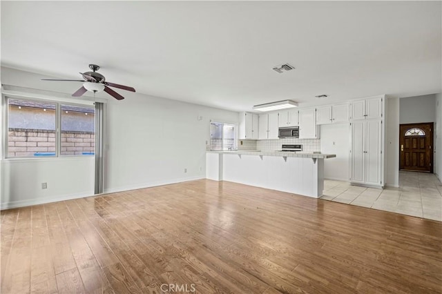 unfurnished living room featuring ceiling fan and light hardwood / wood-style flooring