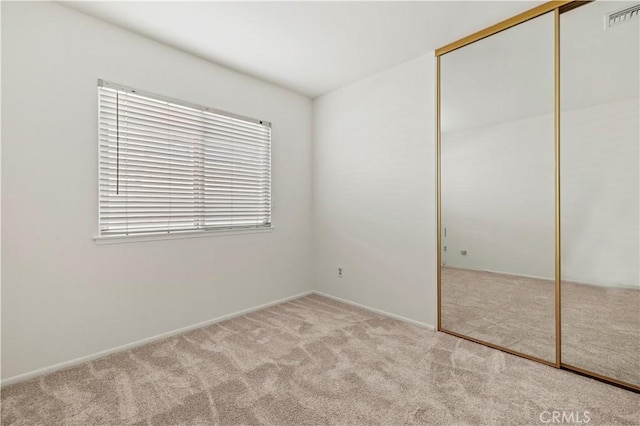 unfurnished bedroom with a closet and light carpet