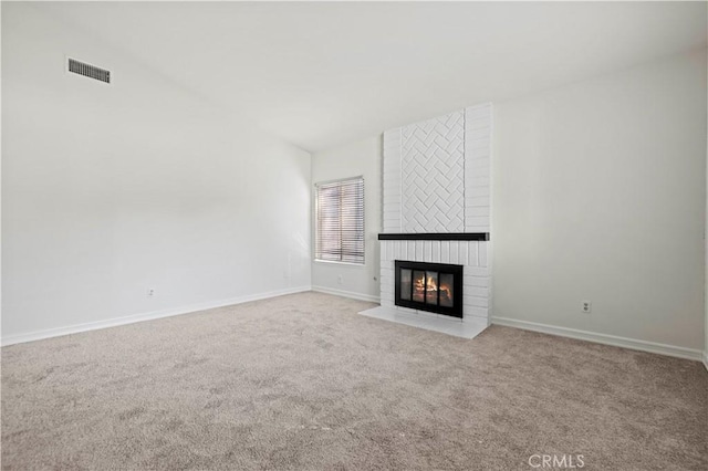 unfurnished living room featuring a brick fireplace and light colored carpet