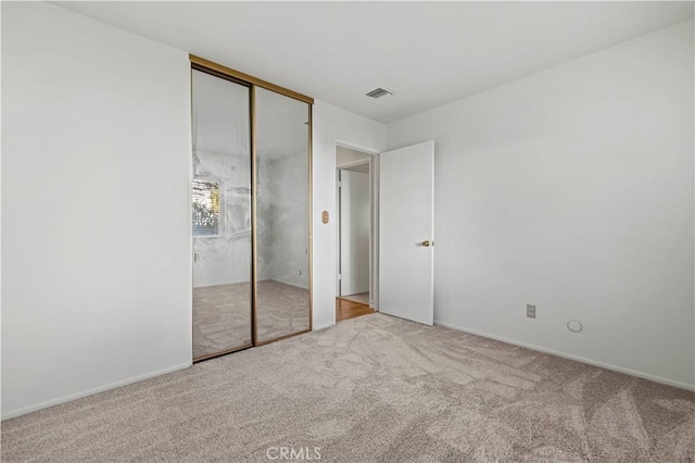 unfurnished bedroom featuring light colored carpet and a closet