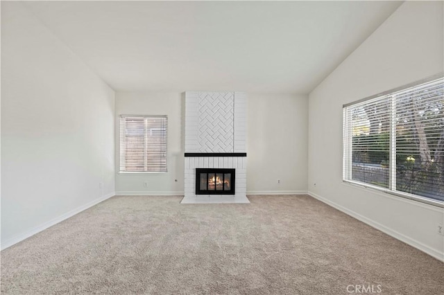 unfurnished living room with light colored carpet, a large fireplace, and lofted ceiling