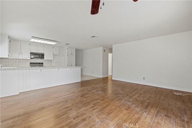 unfurnished living room with ceiling fan and wood-type flooring