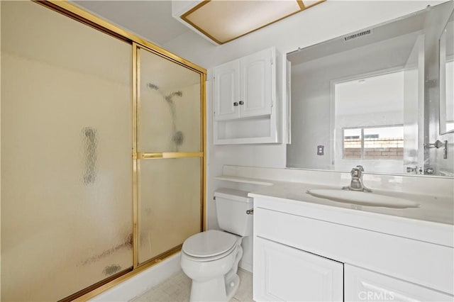 bathroom featuring toilet, vanity, and a shower with door