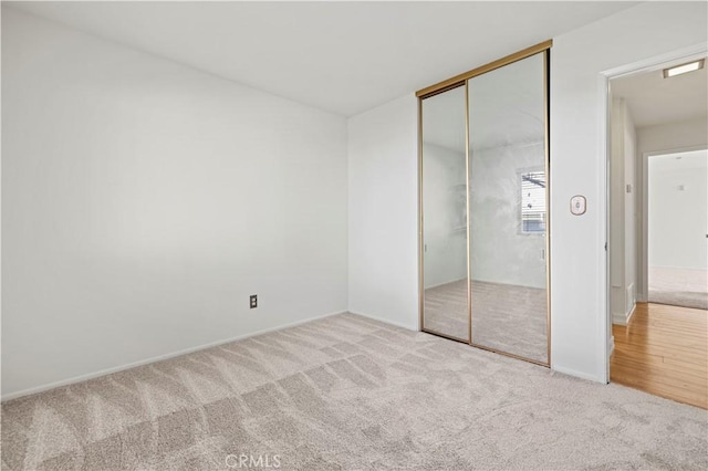 unfurnished bedroom with light colored carpet and a closet