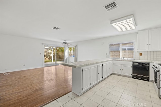 kitchen featuring white cabinetry, kitchen peninsula, black dishwasher, plenty of natural light, and light tile patterned flooring