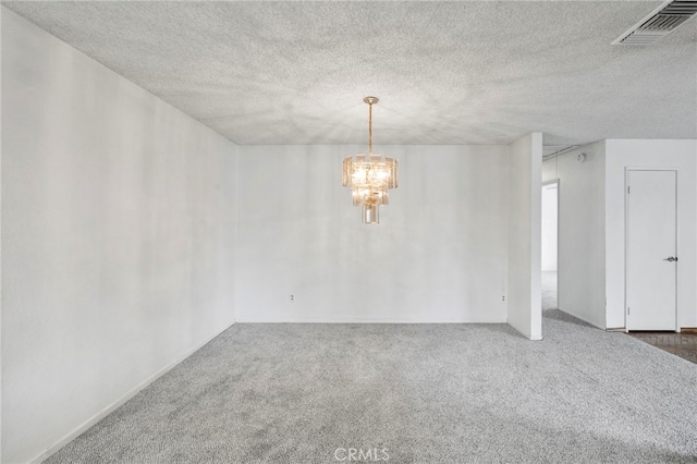 unfurnished room with a textured ceiling, a notable chandelier, and carpet flooring