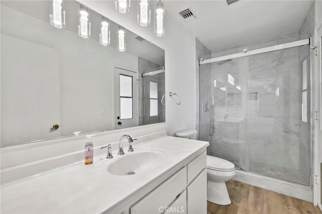 bathroom with a shower with shower door, hardwood / wood-style floors, toilet, and vanity