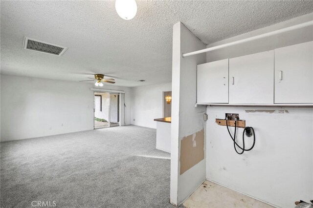 interior space with cabinets, ceiling fan, a textured ceiling, and hookup for a washing machine