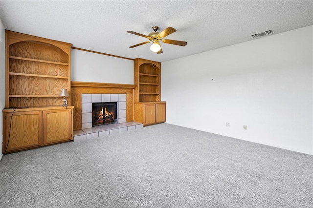 unfurnished living room featuring light colored carpet, a textured ceiling, built in features, and a fireplace