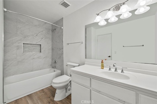 full bathroom with toilet, tiled shower / bath, hardwood / wood-style floors, and vanity