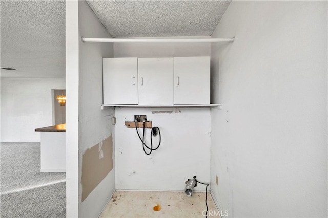 laundry area featuring washer hookup, cabinets, and a textured ceiling