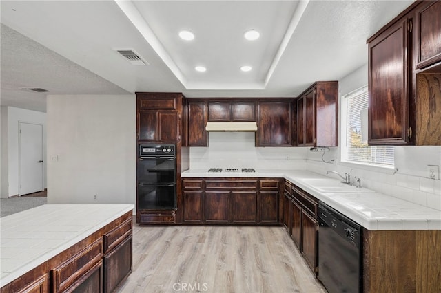 kitchen featuring black appliances, sink, light wood-type flooring, tile counters, and dark brown cabinets