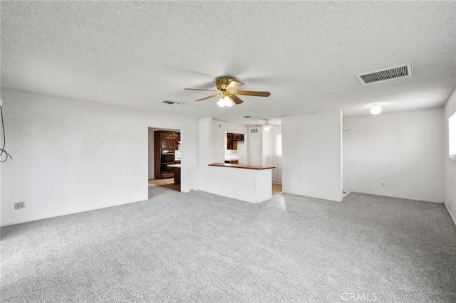 unfurnished living room featuring a textured ceiling, ceiling fan, and light colored carpet