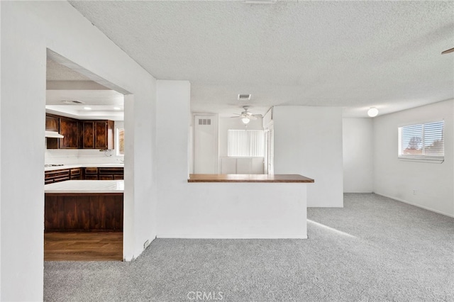 unfurnished living room with ceiling fan, light colored carpet, and a textured ceiling