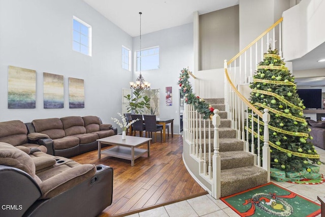 living room with a towering ceiling, a chandelier, and hardwood / wood-style floors