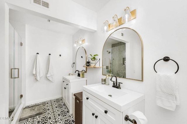 bathroom with a shower with shower door, vanity, and tile patterned floors