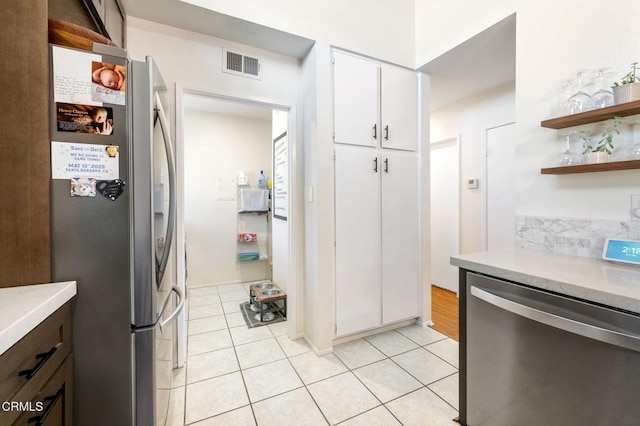 kitchen with light tile patterned floors, stainless steel appliances, and white cabinetry