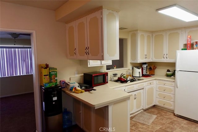 kitchen featuring sink, kitchen peninsula, white cabinets, and white refrigerator