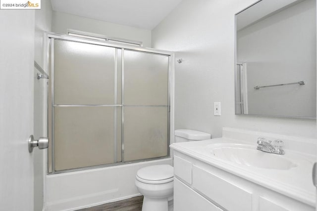 full bathroom with toilet, bath / shower combo with glass door, wood-type flooring, and vanity