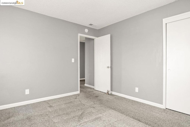 unfurnished bedroom with a textured ceiling and carpet flooring