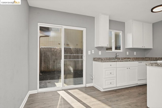 kitchen featuring hardwood / wood-style flooring, dishwasher, white cabinets, and sink