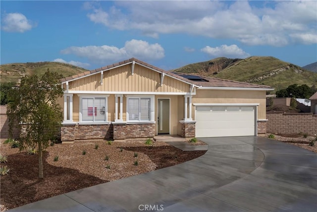 view of front facade with a garage, a mountain view, and solar panels