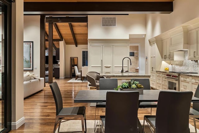 dining area with light hardwood / wood-style flooring, lofted ceiling with beams, sink, and wooden ceiling