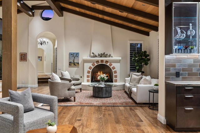 interior space featuring a fireplace, high vaulted ceiling, wooden ceiling, light hardwood / wood-style flooring, and beam ceiling