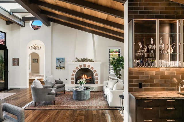 living room featuring lofted ceiling with beams, a fireplace, wood ceiling, and dark hardwood / wood-style floors