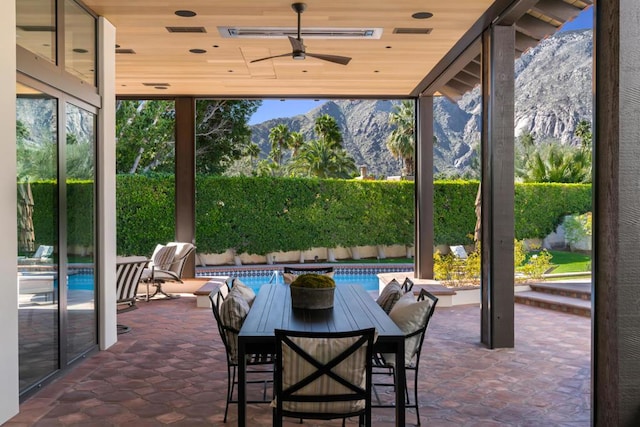 view of patio with ceiling fan, a fenced in pool, and a mountain view