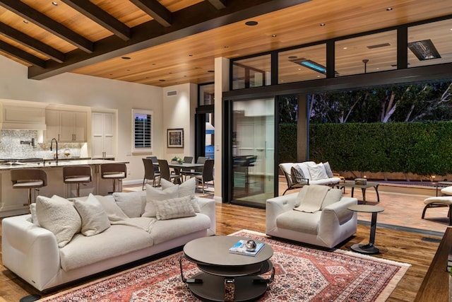 living room with sink, beamed ceiling, wood ceiling, and light wood-type flooring