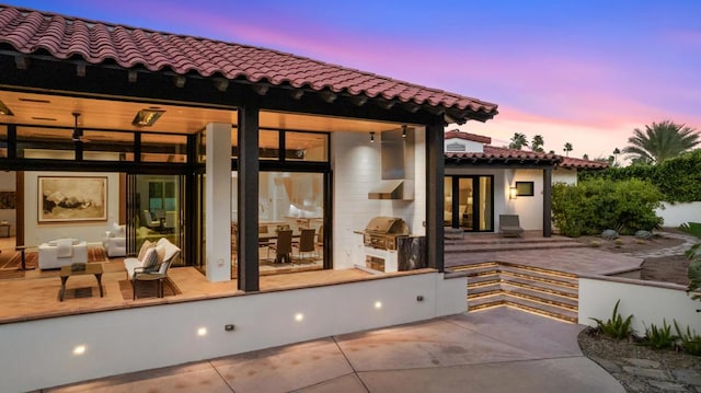 back house at dusk with a patio area and exterior kitchen