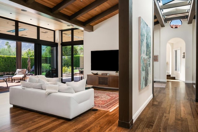 living room featuring dark wood-type flooring, wood ceiling, a towering ceiling, and beamed ceiling