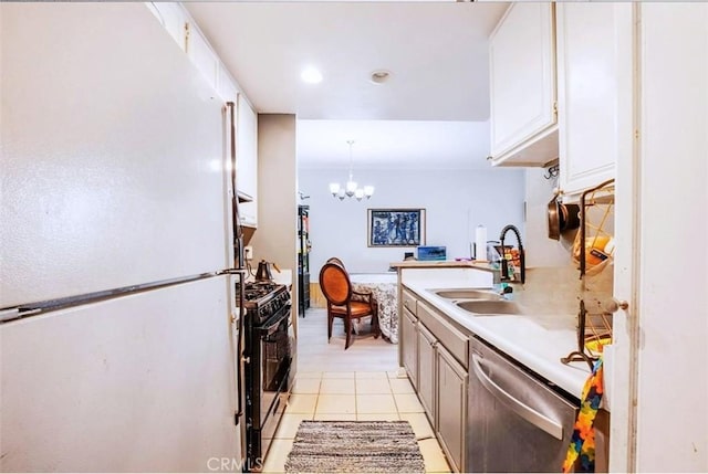 kitchen featuring white fridge, dishwasher, gas range oven, sink, and decorative light fixtures