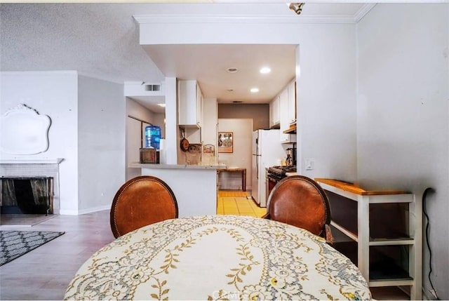 dining area with a textured ceiling, ornamental molding, and light hardwood / wood-style flooring