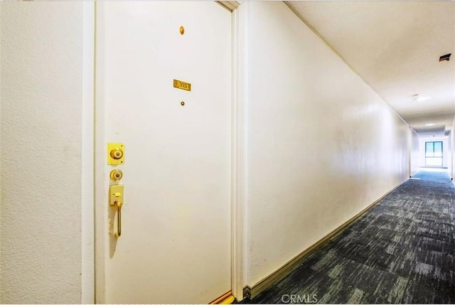 hall featuring dark colored carpet