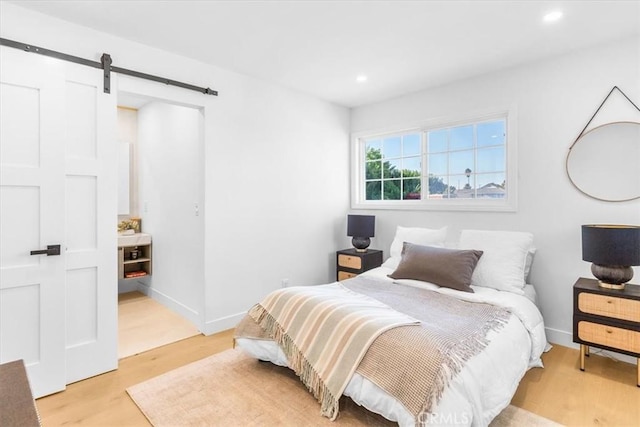 bedroom featuring light hardwood / wood-style floors and a barn door