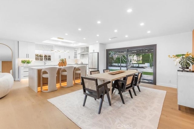 dining space featuring plenty of natural light, light hardwood / wood-style flooring, and a tray ceiling