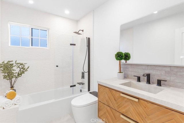 full bathroom featuring tiled shower / bath combo, vanity, toilet, and tasteful backsplash