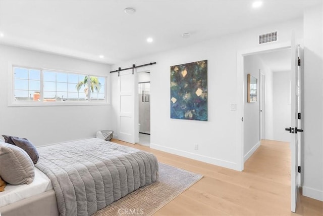 bedroom with light hardwood / wood-style floors and a barn door