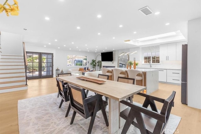 dining room with sink, a tray ceiling, and light hardwood / wood-style floors