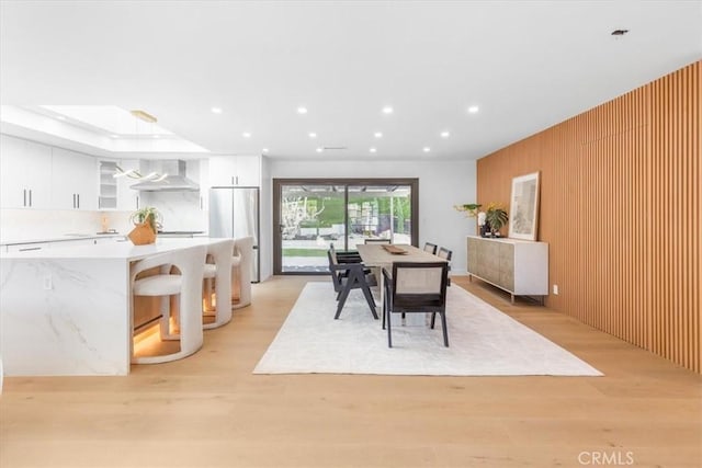 dining area featuring wood walls and light wood-type flooring